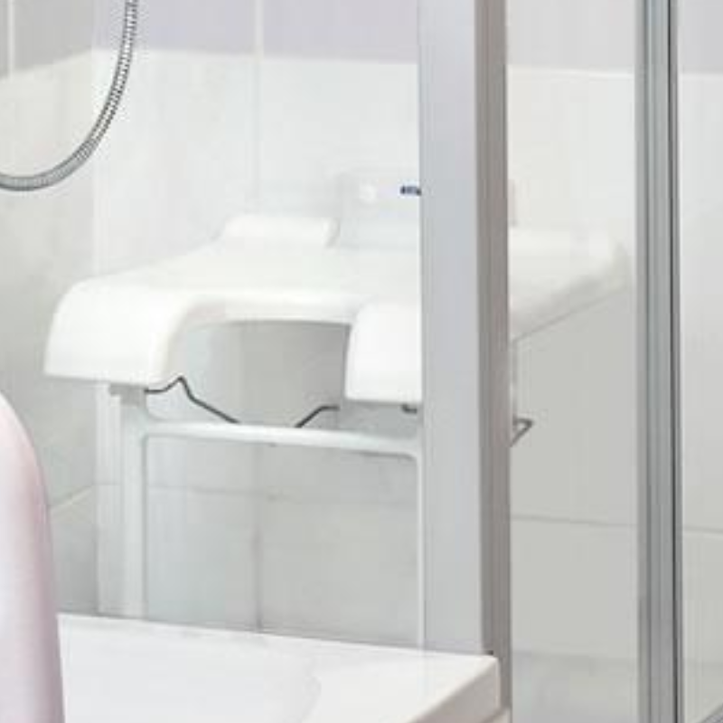 Banco de duche rebatível de parede Sansibar da Invacare, com assento em ferradura e pés de apoio, proporcionando maior conforto, estabilidade e segurança durante a higiene.