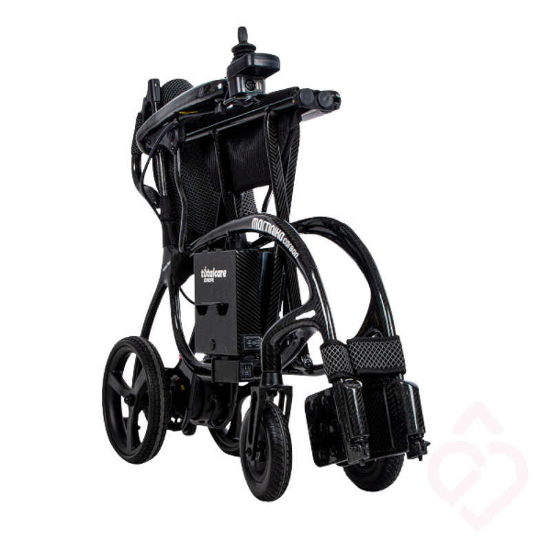 Cadeira de rodas elétrica Martinika Carbon 12Ah apresentada dobrada, com estrutura compacta em fibra de carbono. O sistema dobrável facilita o transporte e a arrumação, proporcionando maior praticidade nas deslocações e no dia a dia.