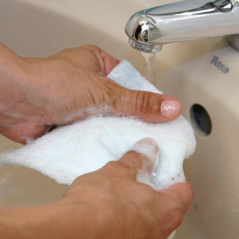 Esponja ensaboada ativada com água, formando espuma para facilitar uma higiene corporal prática e eficaz.