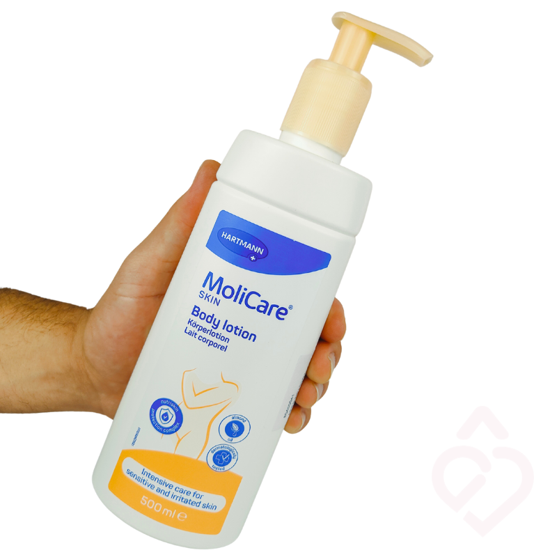 Frasco de MoliCare Skin Body Lotion de 500 ml com doseador, segurado numa mão