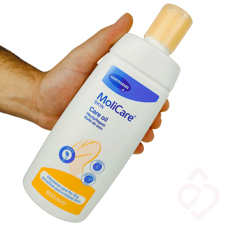 Frasco de óleo MoliCare Skin Care Oil de 500 ml segurado numa mão, mostrando a embalagem.