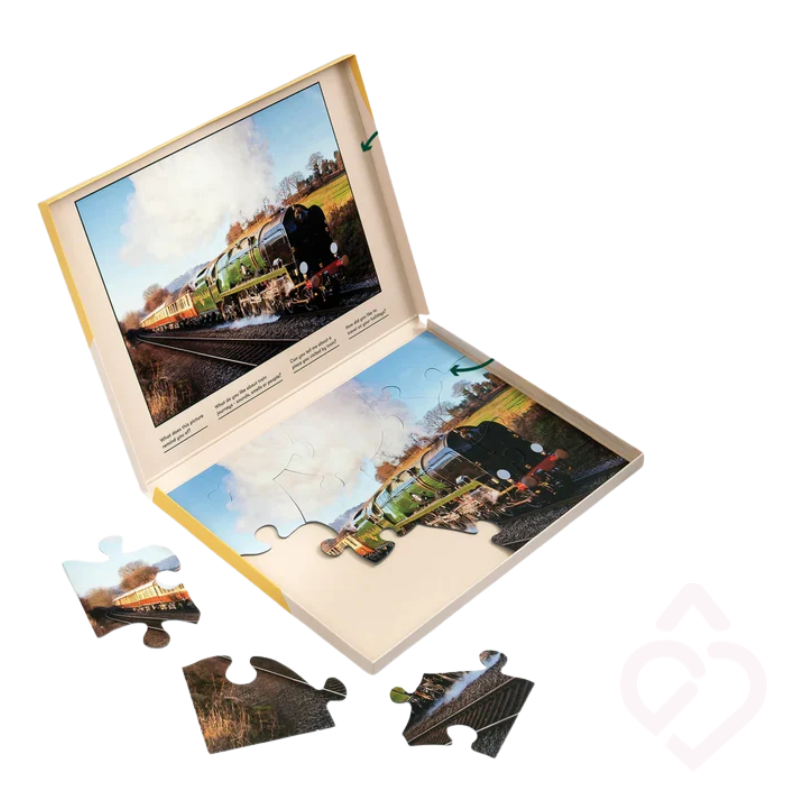 Puzzle Relish Orient Express de 13 peças, apresentado na caixa com imagem de referência para facilitar a montagem. As peças grandes favorecem o manuseamento e a participação. A atividade estimula a atenção, a memória e a coordenação, podendo também incentivar a conversa e a partilha de memórias em pessoas idosas ou com demência.