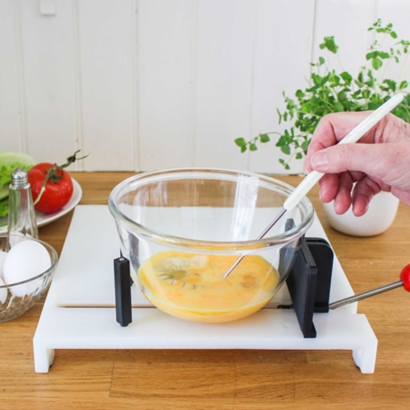 Tábua para preparação de alimentos com suportes que mantêm a taça estável enquanto os alimentos são misturados, facilitando a preparação com maior autonomia.
