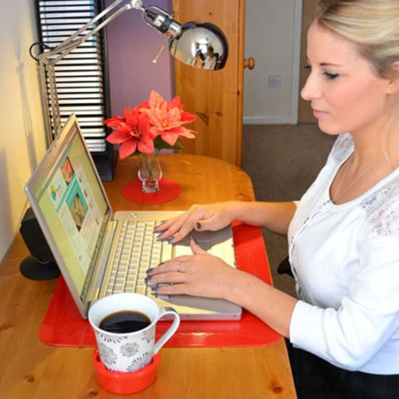 Tapete antiderrapante vermelho sob um computador portátil e uma chávena, ajuda a manter os objetos estáveis durante a utilização